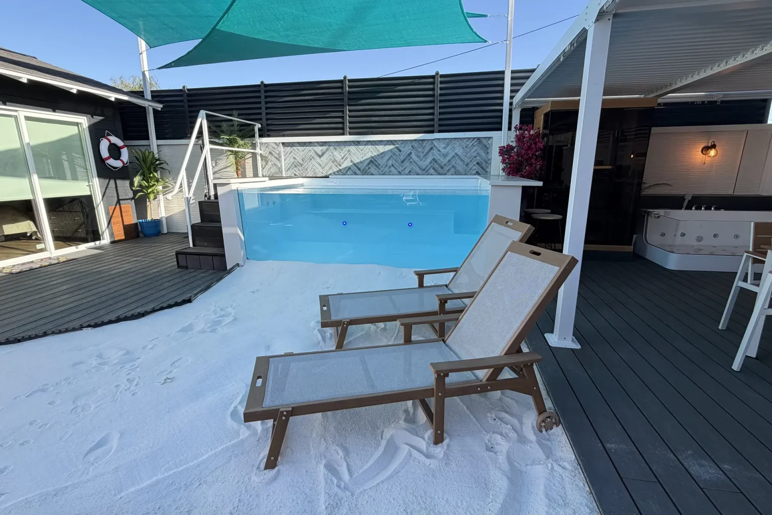 Heated glass pool and lounge deck in daylight